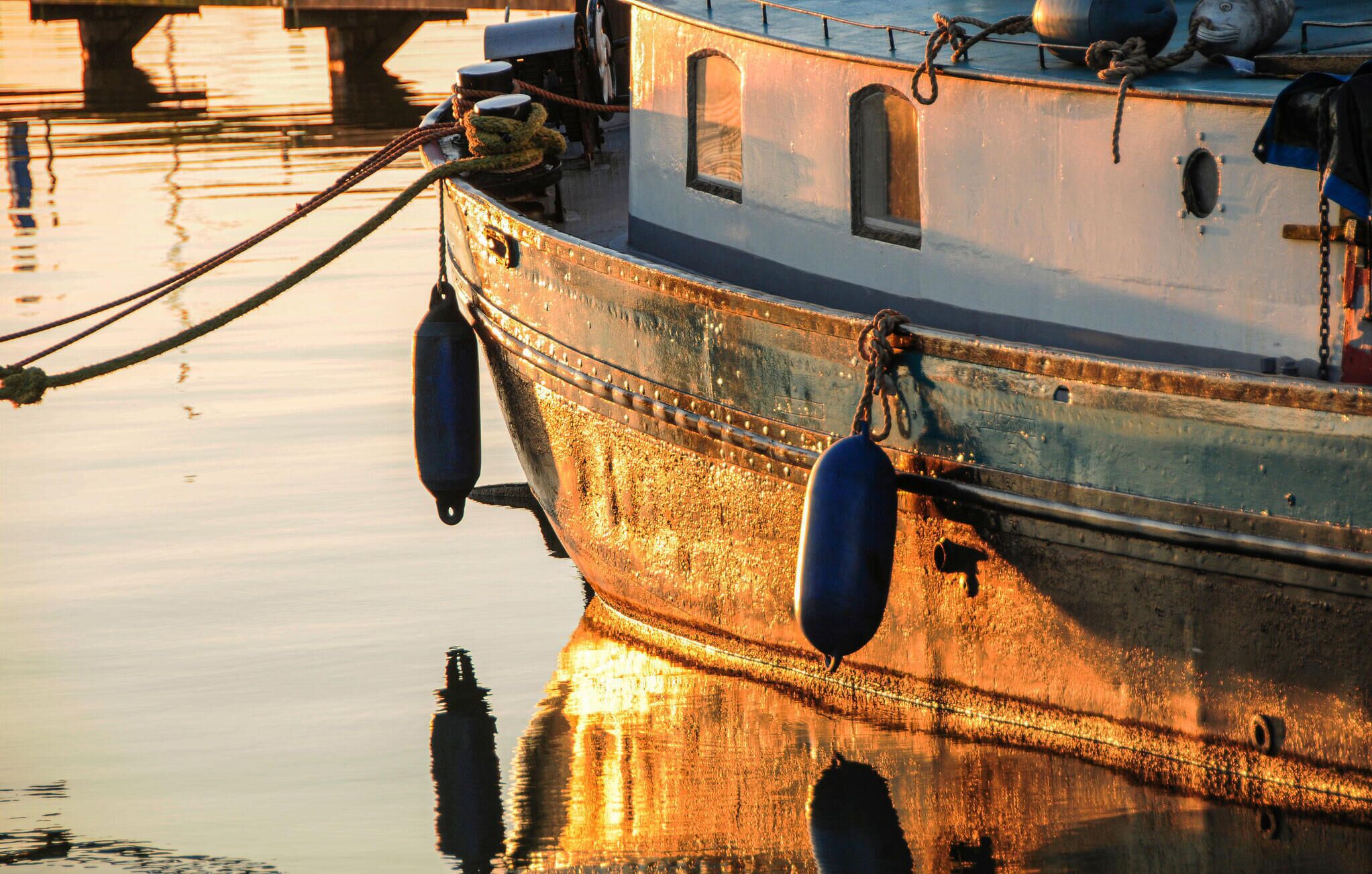 Ein Boot liegt an einem Steg, das ruhige Wasser spiegelt die Struktur wider.
