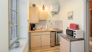 A compact kitchen with wooden cabinets, a coffee maker, a toaster, and a microwave. - 1 bedroom awesome apartment in Krakow am See (Krakow am See)
