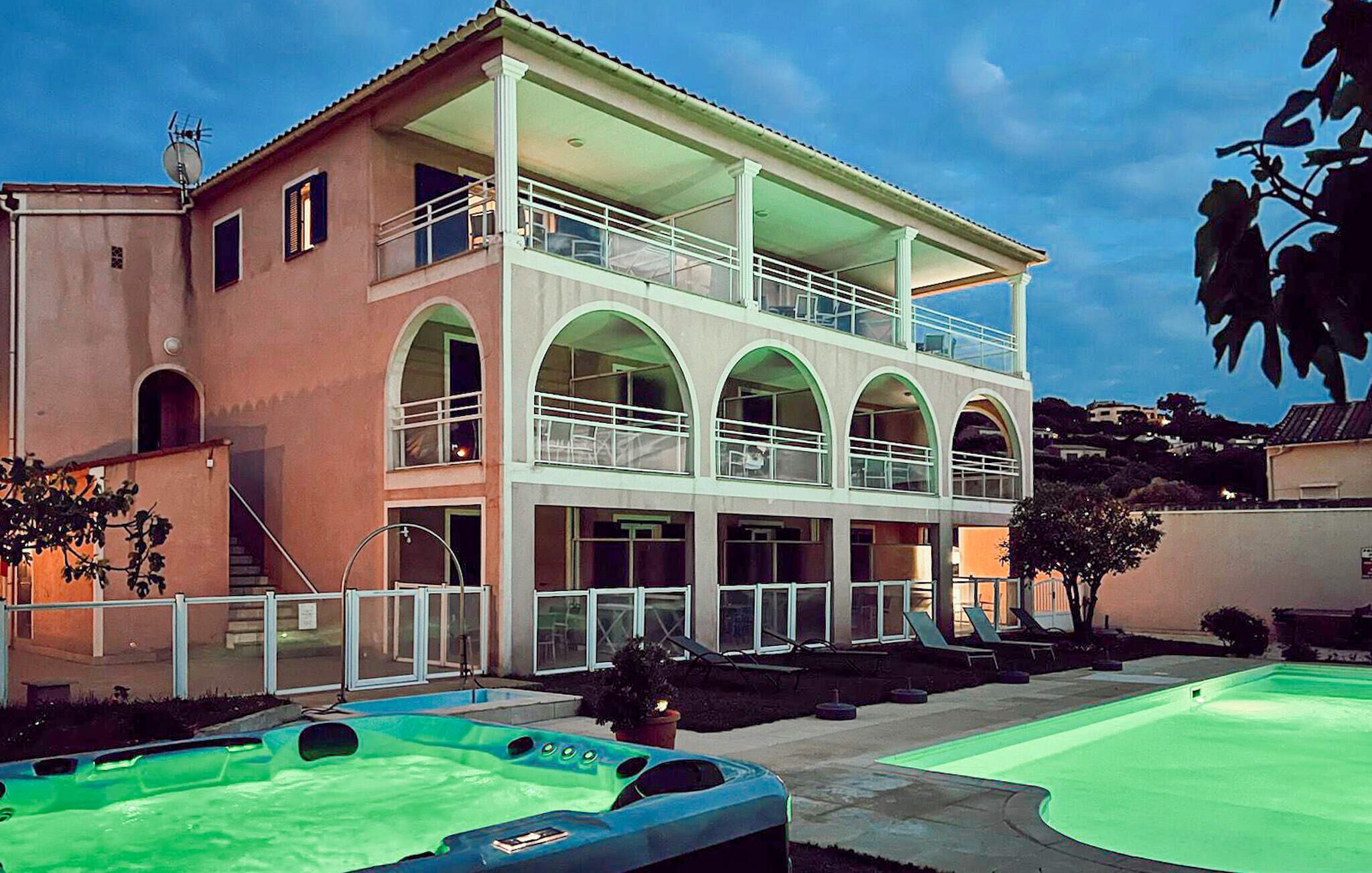 Un edificio a due piani con un balcone, una piscina e una vasca idromassaggio.