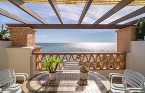 A terrace with a view of the sea, featuring a tiled table, potted plants, and white plastic chairs. - Gorgeous apartment in Torrox Costa with WiFi (Torrox Costa)