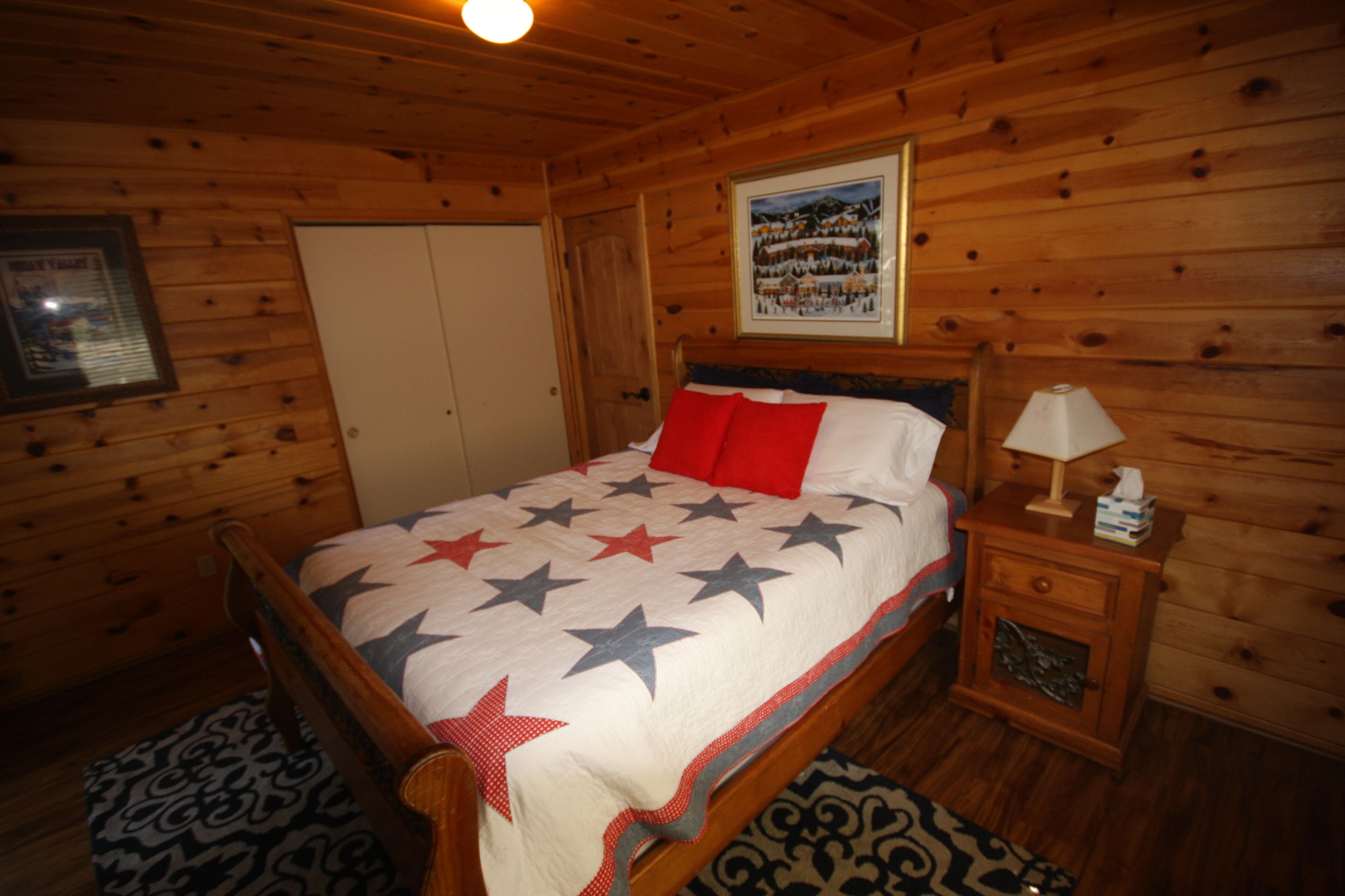 Un dormitori d'estil cabana de fusta amb llit, taulella de nit i calaixera.
