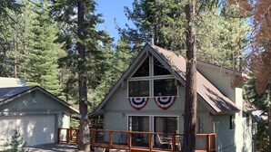A cabin with a porch, a garage, and a deck.
