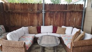 A wicker sectional sofa with a matching ottoman and a small coffee table in a covered outdoor area. - Cozy cabin-like 2 bedroom home (Reno)