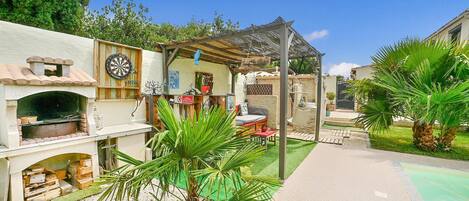 A courtyard with a brick oven, a dartboard, and a hammock.