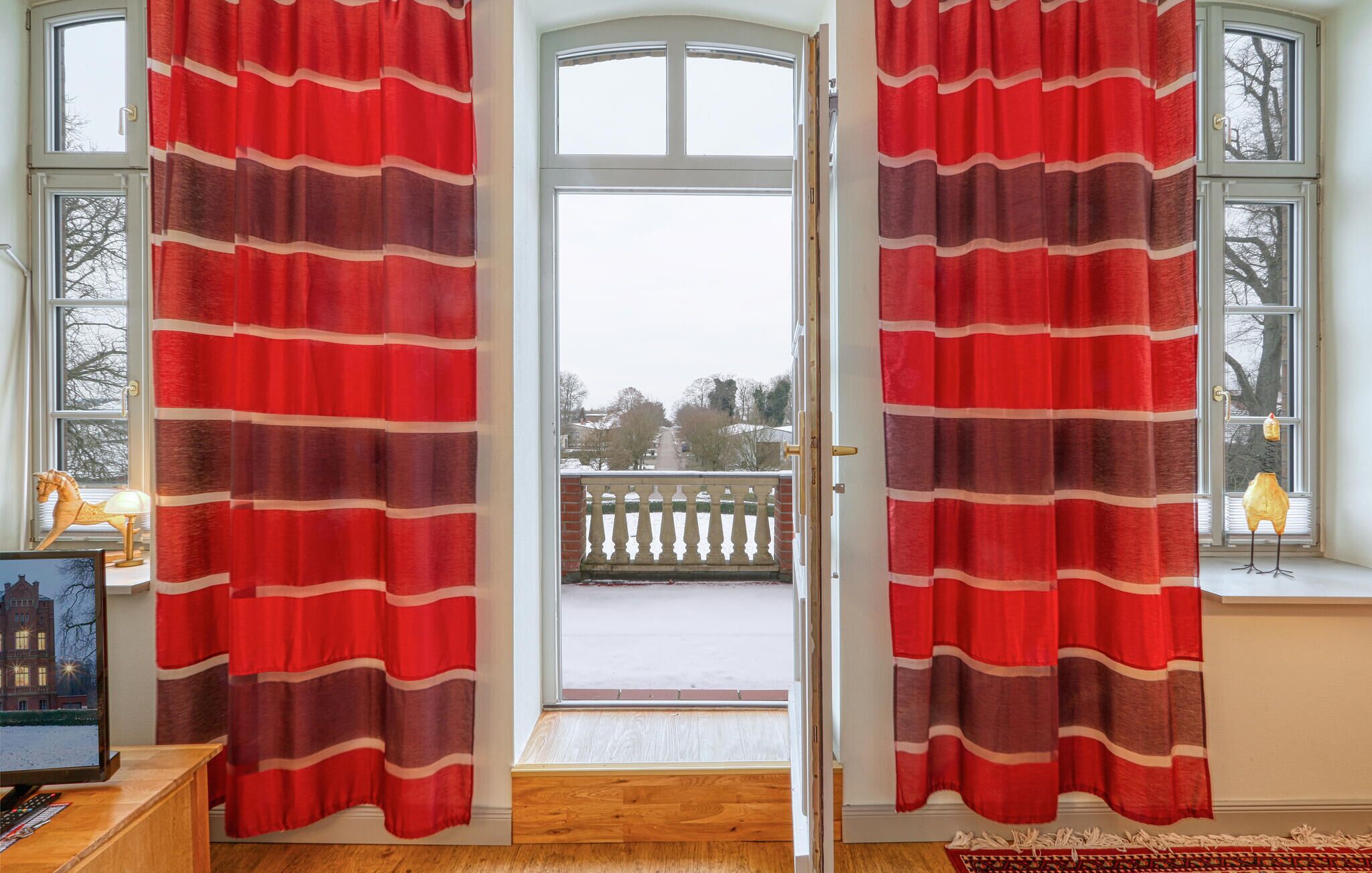 Ein Zimmer mit einem großen Fenster und Blick auf eine verschneite Landschaft.