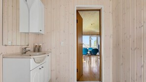 Un pasillo estrecho con interior de madera que lleva a un comedor con sillas azules y una mesa.