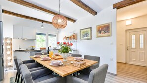 A modern kitchen with white cabinets, a wooden dining table, and grey upholstered chairs.
