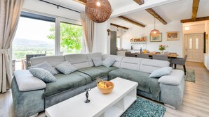 A modern living room with a sectional sofa, a white coffee table, and a hanging light fixture.