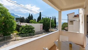 A balcony with a table and chairs, overlooking a residential area with trees and a mountain in the background. - Nice apartment in Duce with WiFi (Duce)