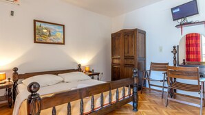 A bedroom with a wooden bed, a wooden wardrobe, a television mounted on the wall, and a red curtain. - Nice apartment in Duce with WiFi (Duce)
