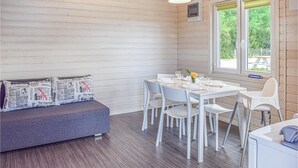 A cozy room with a grey sofa, white chairs, and a table set for dining. - Pet friendly home in Rewal with WiFi (Rewal)