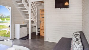 A modern interior with a staircase, a TV mounted on the wall, a sofa, and a dining area with a table and chairs. - Pet friendly home in Rewal with WiFi (Rewal)
