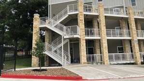 Un edificio de varios pisos con fachada de piedra y barandillas blancas.