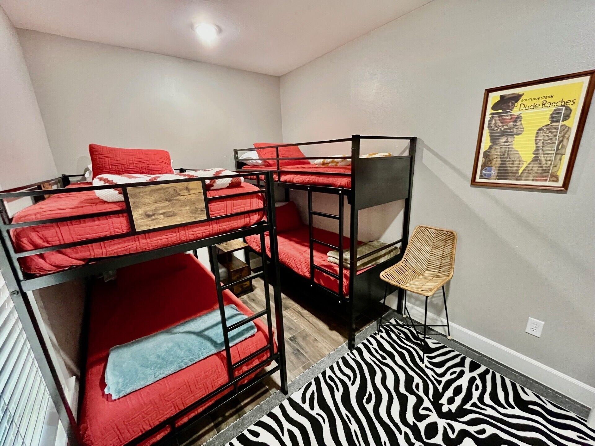 A bunk bed room with a zebra-patterned rug, a framed picture on the wall, and a chair.