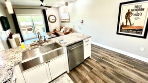 Una cocina moderna con encimera de granito, electrodomésticos de acero inoxidable y suelo de madera.