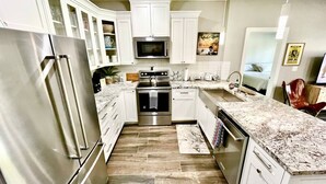 Una cocina moderna con armarios blancos, electrodomésticos de acero inoxidable y encimera de mármol.