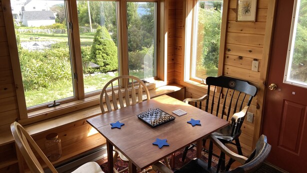 Une cabane en bois avec une table à manger, des chaises et un jeu d’échecs.