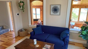 Un salon chaleureux avec un canapé bleu, une table basse en bois et une fenêtre donnant sur l’extérieur.
