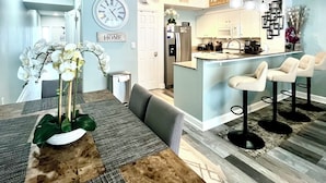 A modern kitchen with a central island, bar stools, and a dining area with a wooden table and chairs.
