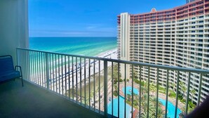 A balcony with a view of a beach and a hotel building.