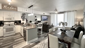 A modern kitchen with a central island, white cabinetry, and a dining area with a table and chairs.