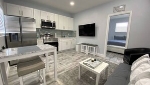 A modern kitchen with white cabinets, stainless steel appliances, and a grey tiled backsplash. - Welcome to Maya's Blue Lagoon Luxury Suite (Fort Lauderdale)