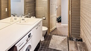 A bathroom with a white sink, a mirror, a toilet, and a washing machine.