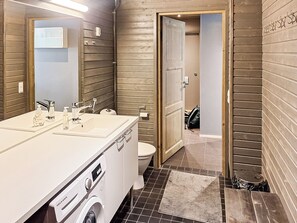 A bathroom with a white sink, a mirror, a toilet, and a washing machine.