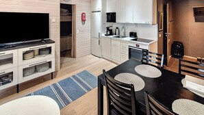 A compact living space with a kitchenette, a dining area, and a television.