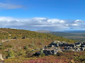 A mountainous landscape with a clear sky, rocky terrain, and sparse vegetation.