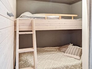 Una litera con escalera de madera, colchón y almohadas.