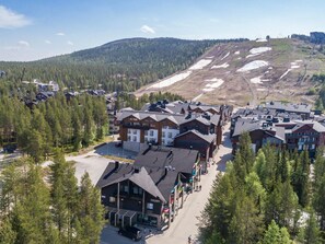 A ski resort with multiple buildings, including a lodge and a restaurant, surrounded by dense forests and a mountain backdrop.