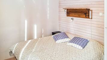 A bedroom with a bed, a nightstand, a wooden headboard, and a wall-mounted light fixture.