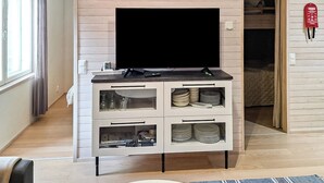 A modern living room with a flat-screen TV on a white cabinet, a window with curtains, and a visible door leading to another room.