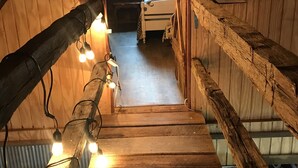 Una escalera de madera que conduce a un dormitorio con techo inclinado y tragaluces.