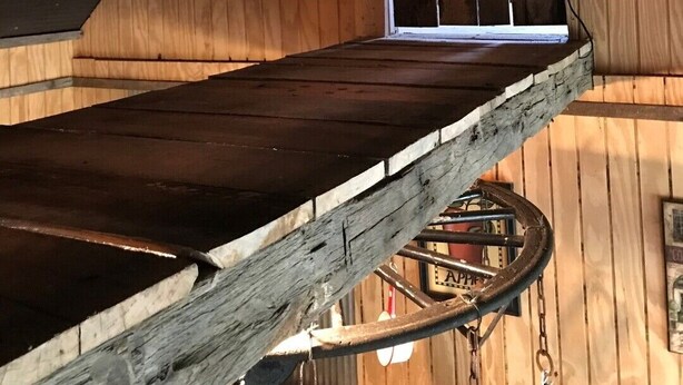 Un interior de madera con una escalera rústica, vigas a la vista y lámparas colgantes.