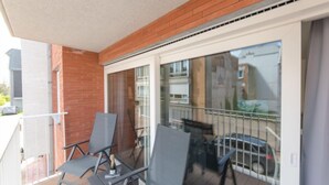 A balcony with two chairs and a table, a glass door, and a view of a residential area. - Medano 1.2 with balcony by Interhome (Bredene)