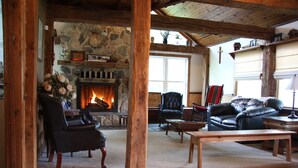 Un salon chaleureux avec une cheminée en pierre, des meubles en cuir et un plafond en bois.