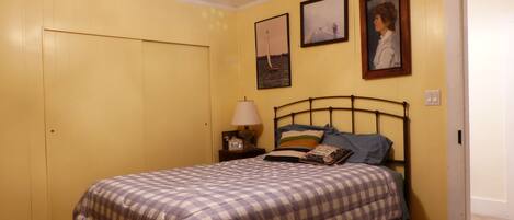 A bedroom with a bed, a nightstand, a lamp, and two framed pictures on the wall.