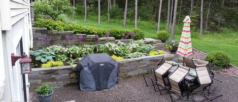 A patio with a grill, outdoor furniture, and a striped umbrella.