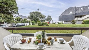 Une table dressée à l’extérieur, offrant une vue sur un quartier résidentiel, avec des maisons et une voiture.