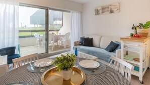 Un salon moderne comprenant un coin repas, un canapé, une table basse et une vue dégagée grâce à de grandes portes-fenêtres coulissantes.