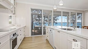 Een moderne keuken met witte kasten, een ingebouwde oven en een groot raam met uitzicht op een prachtig landschap.