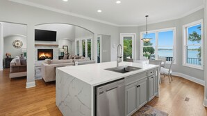 Una cocina moderna con lavavajillas integrado, un comedor con vistas y una sala de estar con chimenea.