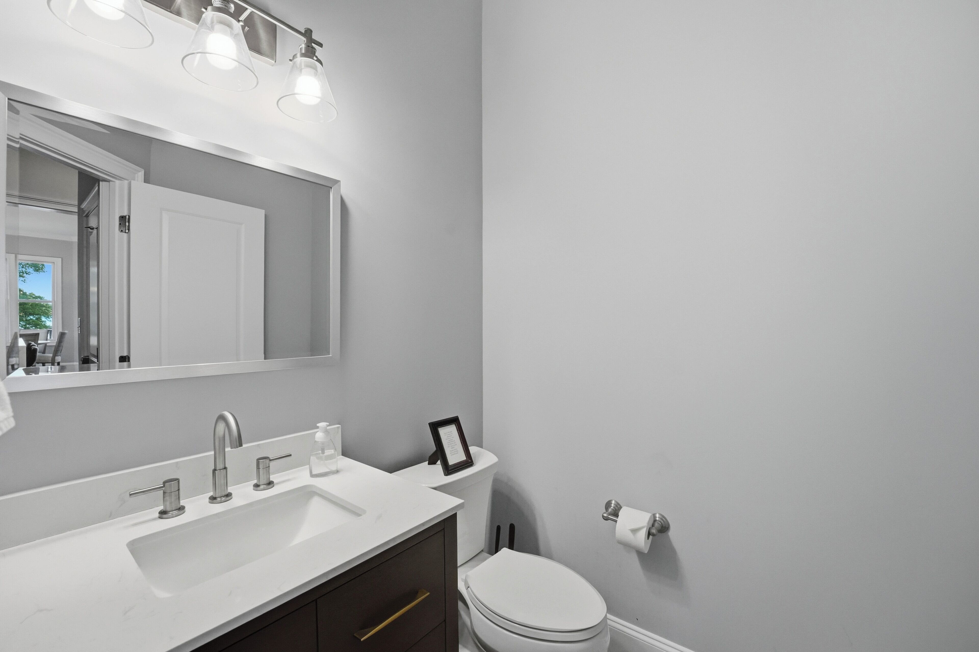 Une salle de bain avec un lavabo blanc, un miroir, des toilettes et un tableau encadré au mur.