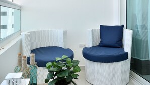 A balcony with wicker chairs, a potted plant, and decorative wall art.