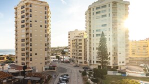Un immeuble résidentiel de grande hauteur doté de nombreux balcons, d’un espace de stationnement et offrant une vue sur la mer.