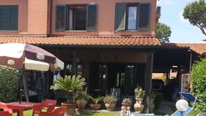 A villa with a covered patio, outdoor seating, and potted plants. - 3 bedrooms villa  Sleeps 6 with Garden (Roma)