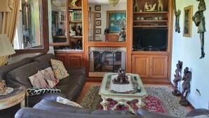 A living room with a sofa, a coffee table, a fireplace, and various decorative items. - 3 bedrooms villa  Sleeps 6 with Garden (Roma)