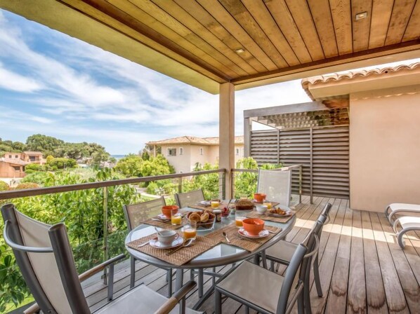 A balcony with a table set for breakfast, overlooking a residential area and greenery.